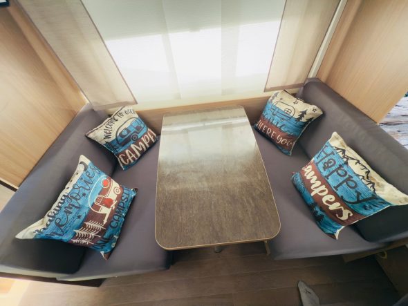 Sitzecke Gemütliche Sitzecke mit grauem Sofa, Holztisch und dekorativen Kissen.