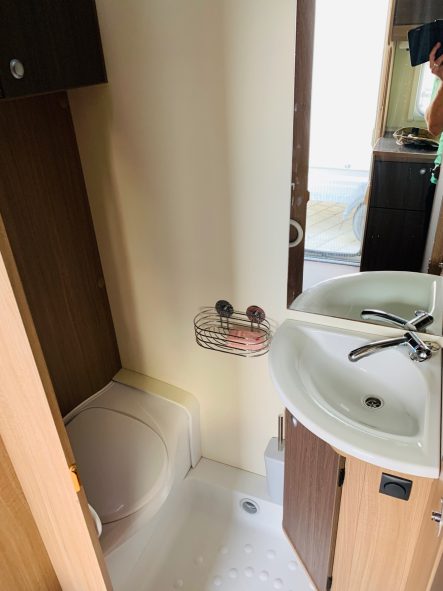 Toilette Kleines Badezimmer mit Toilette und Waschbecken, hell erleuchtet.