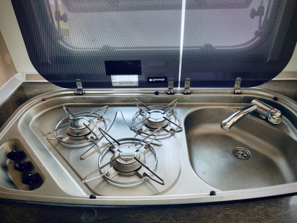 Moderne Küchenzeile mit drei Gasbrennern und Waschbecken.