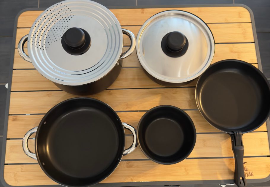 Töpfe und Pfanne Kochgeschirrset mit Töpfen, Pfannen und Deckeln auf einem Holzuntergrund.