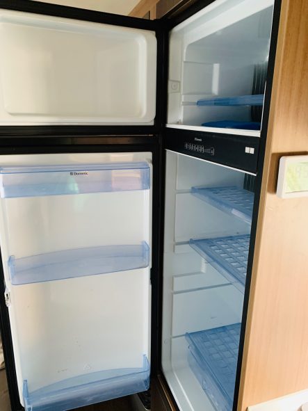 großer Kühlschrank mit Gefrierfach Offener Kühlschrank mit leeren Regalen und Schubladen.