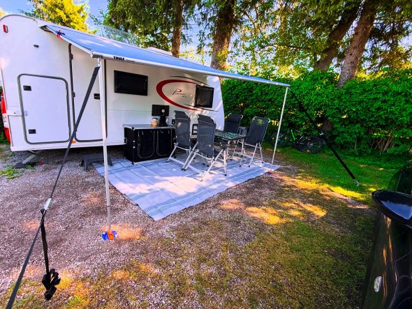 Wohnwagen mit Markise, vier Stühle und Tisch